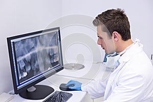 Attentive dentist examining x-ray report on computer