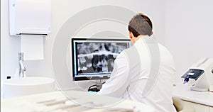 Attentive dentist examining x-ray report on computer