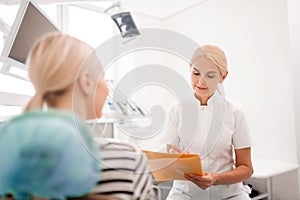 Attentive dentist writing complains of her patient.