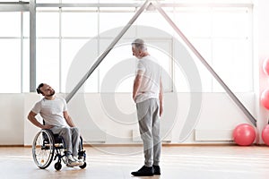 Attentive disabled man training in the gym with the orthopedist