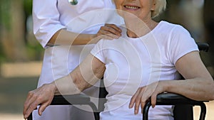 Attentive doctor stroking shoulder of disabled patient professional medical care