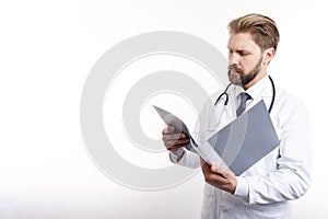 Attentive Doctor in White Scrubs Examining Medical Documentation