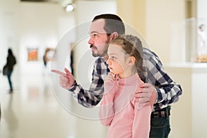 Attentive father and daughter exploring expositions in museum