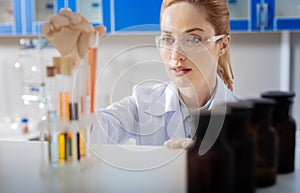 Attentive female person examining orange liquid