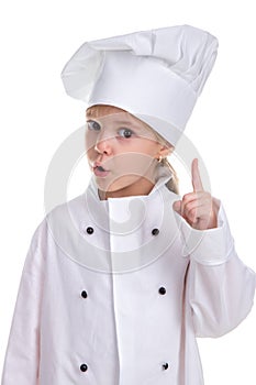 Attentive girl chef white uniform isolated on white background, looking straight at the camera with a pointing finger up