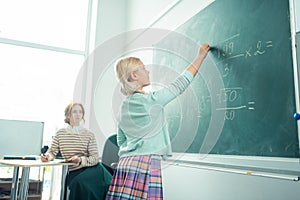 Attentive girl working at the blackboard during maths class.