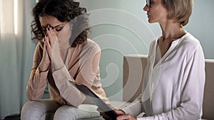 Attentive lady psychologist tying to comfort depressed female patient, problems
