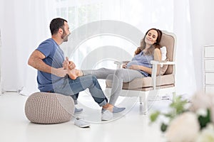 Attentive man massaging pregnant woman feet