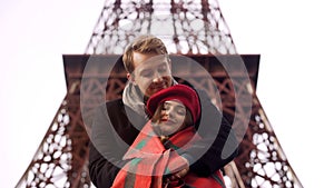 Attentive man wrapping his frozen beloved lady in blanket, openair date in Paris