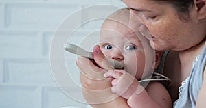 Attentive mother feeds excited baby daughter from spoon