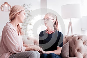 Attentive mother looking at her teenage daughter while sitting with her