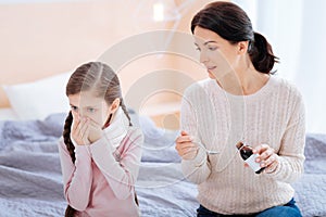 Attentive mother persuading her child to drink the mixture