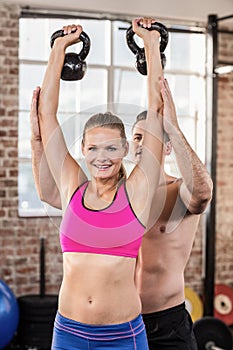 Attentive muscular trainer show how to lift kettlebells