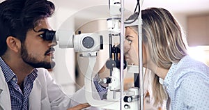 Attentive optometrist examining female patient on slit lamp