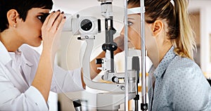 Attentive optometrist examining female patient on slit lamp