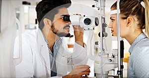 Attentive optometrist examining female patient on slit lamp