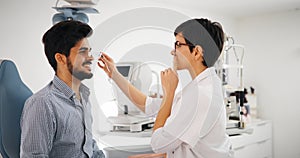 Attentive optometrist examining female patient on slit lamp