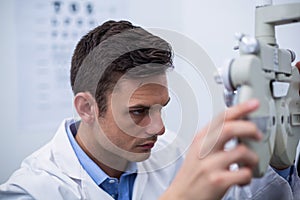 Attentive optometrist looking through phoropter