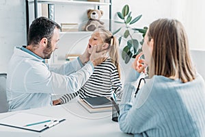 attentive pediatrist examining throat of child