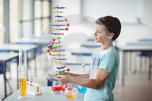 Attentive schoolboy experimenting molecule model in laboratory