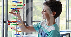 Attentive schoolboy experimenting molecule model in laboratory