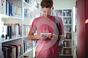 Attentive schoolboy using digital tablet in library