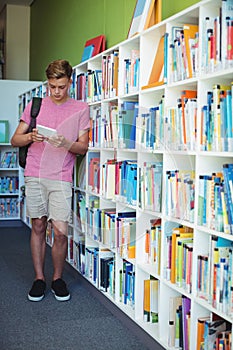 Attentive schoolboy using digital tablet in library