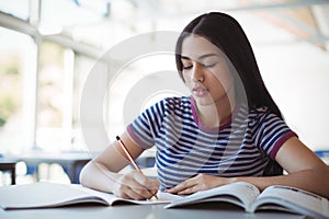 Attentive schoolgirl doing homework in classroom