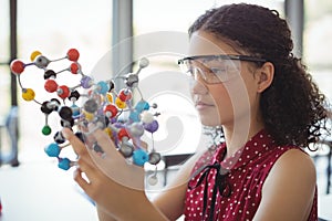 Attentive schoolgirl experimenting molecule model in laboratory