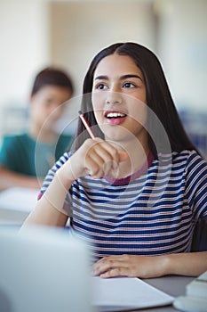 Attentive schoolgirl studying in classroom