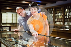 Attentive senior couple examining objects applied art in museum