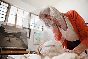 Attentive senior woman shaping a molded clay