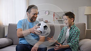 Attentive smiling volunteer giving orphan boy soccer ball, dreams come true