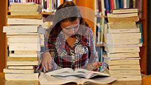 Attentive student studying in the library surrounded by books