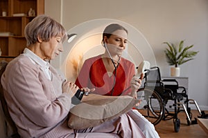 Attentive woman healthcare worker taking blood pressure of senior woman