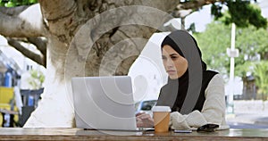 Attentive woman in hijab using laptop 4k