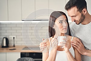 Attentive young husband hugging his wife at home