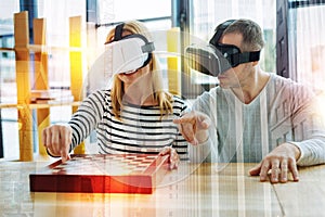 Attentive young people playing chess while wearing virtual reality glasses