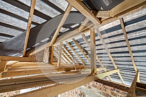 Attic of a building under construction with wooden beams of a roof structure and brick walls