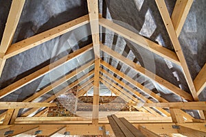 Attic of a building under construction with wooden beams of a roof structure and brick walls