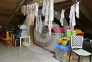 Attic with many throw things and clothes hung out to dry