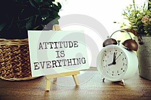 Attitude is everything text message on paper card with wooden easel on wooden table background, inspiration motivation concept