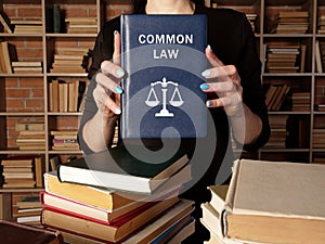Attorney holds COMMON LAW book. Common law is a body of unwritten laws based on legal precedents established by the courts
