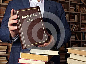 Attorney holds MARTIAL LAW book. Martial law is the temporary imposition of direct military control of normal civil functions or