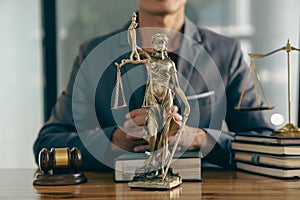 Attorney in the office with Gail Brass. statue of justice and lawyer working on laptop and the female judge`s hammer, or Eustitia.