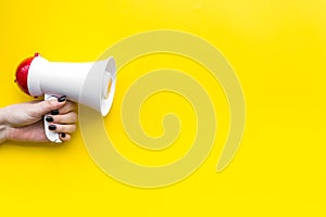 Attract attention concept. Megaphone in hand on yellow background top view copy space photo