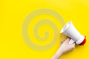 Attract attention concept. Megaphone in hand on yellow background top view copy space