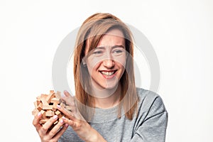 Attractive 24 year old business woman looking confused with wooden puzzle.