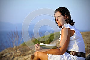 Attractive 40s mature woman reading and looking at horizon pensive