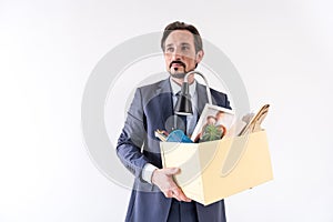 Attractive adult bearded man is holding box with his things